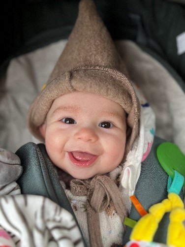 A baby wearing a pointed hat smiling.