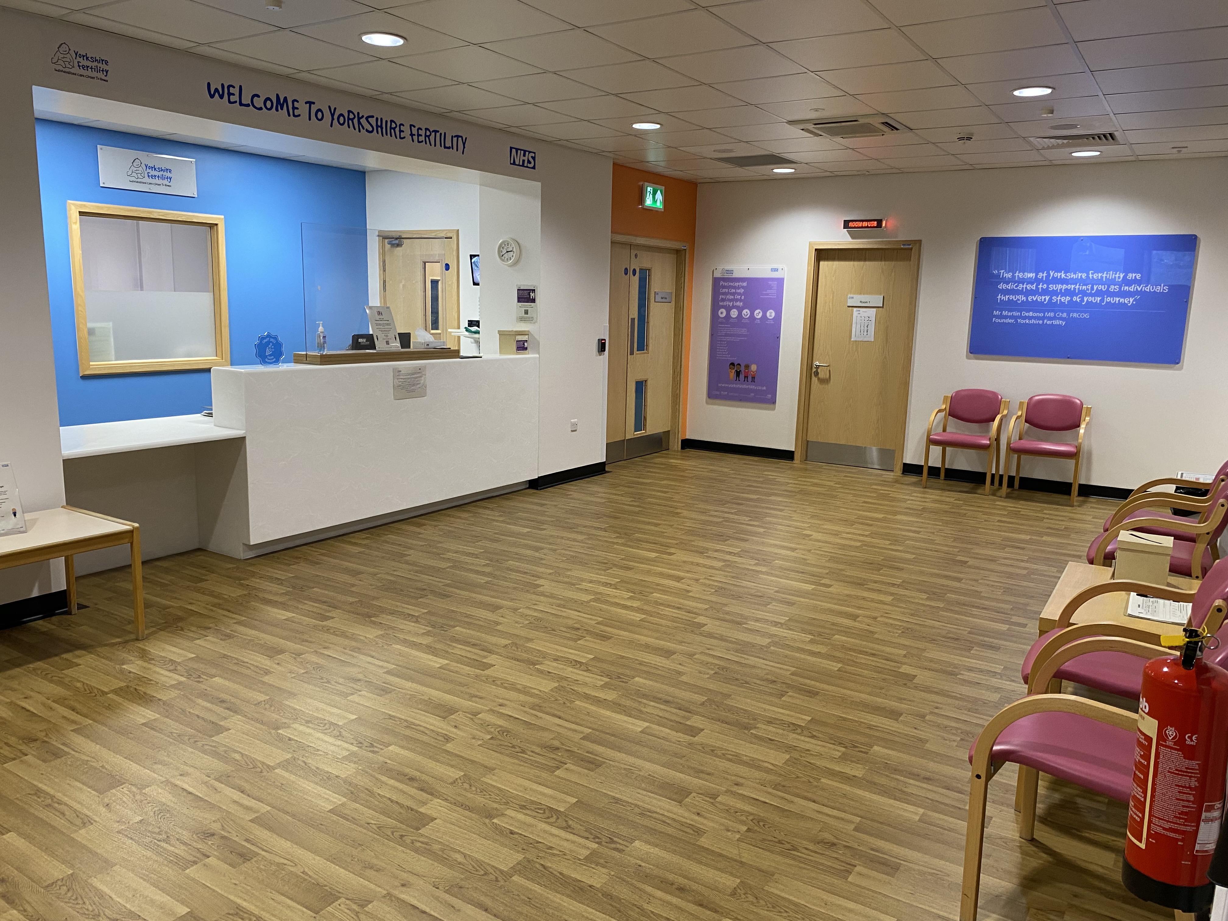 The reception area of Yorkshire Fertility features wooden flooring and chairs arranged against the wall.