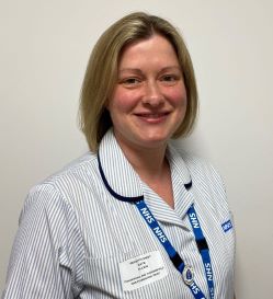 A person with blonde hair wearing a white uniform and blue lanyard