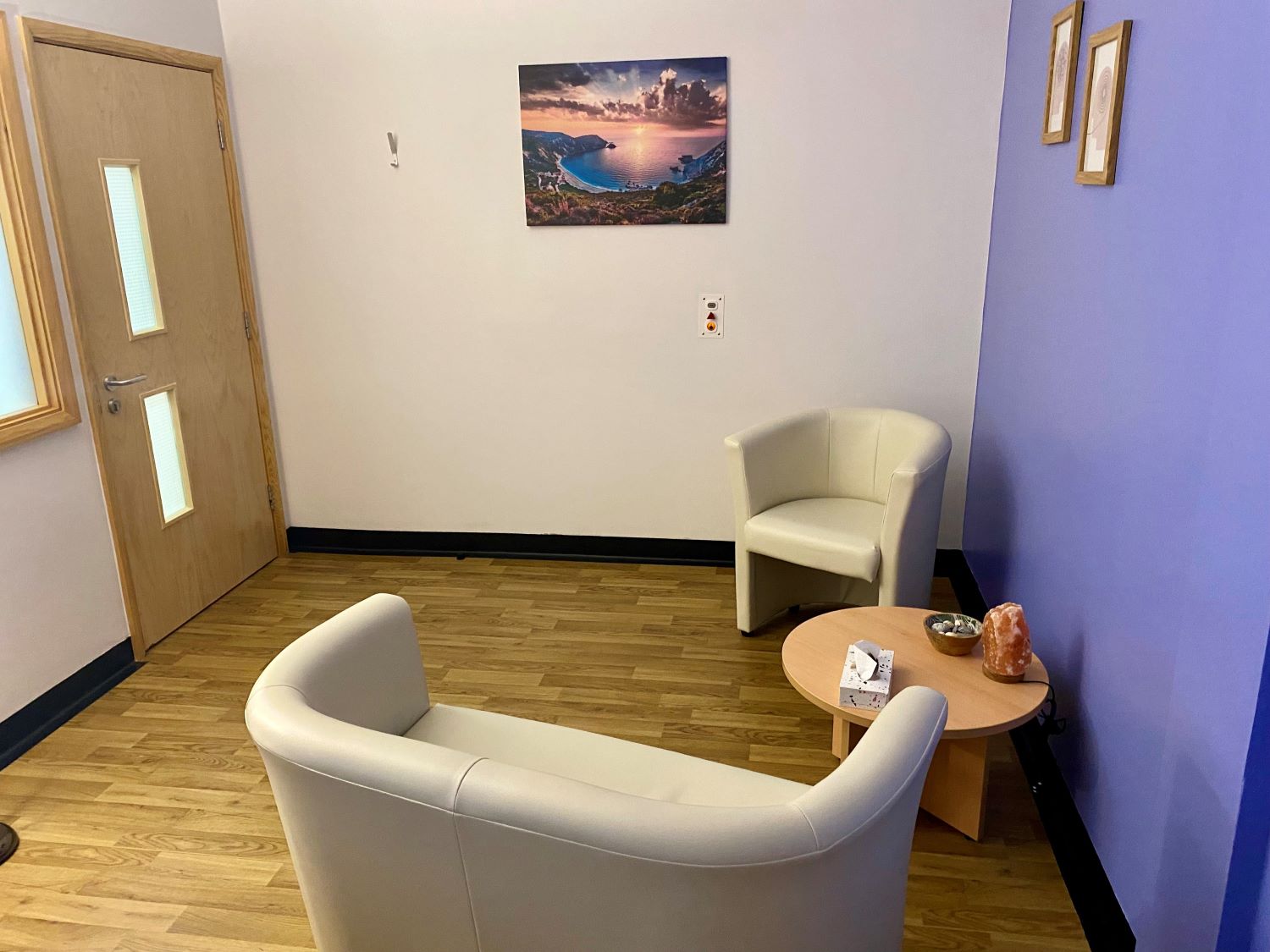 A well-lit room with a cream sofa, cream chair and a small round table.