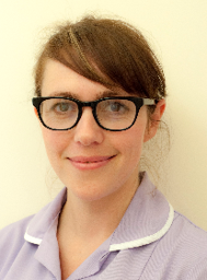 A person with brunette hair and wearing glasses and a purple uniform.
