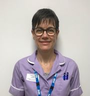 A person wearing glasses, with black hair with a fringe, and a purple uniform.