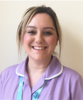 A person with blonde hair smiling in purple uniform.